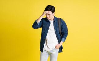 Portrait of Asian male student posing on yellow background photo