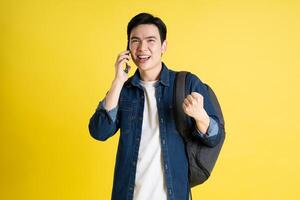 Portrait of Asian male student posing on yellow background photo