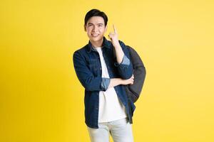 Portrait of Asian male student posing on yellow background photo