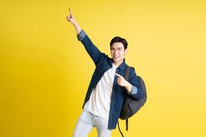 Portrait of Asian male student posing on yellow background photo