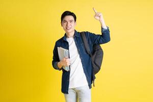 retrato de asiático masculino estudiante posando en amarillo antecedentes foto