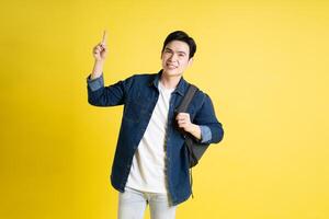 Portrait of Asian male student posing on yellow background photo