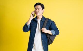 retrato de asiático masculino estudiante posando en amarillo antecedentes foto