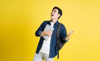 Portrait of Asian male student posing on yellow background photo