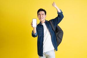 Portrait of Asian male student posing on yellow background photo