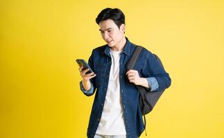 Portrait of Asian male student posing on yellow background photo