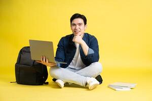 Portrait of Asian male student posing on yellow background photo