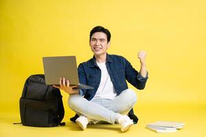 Portrait of Asian male student posing on yellow background photo