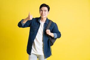 Portrait of Asian male student posing on yellow background photo