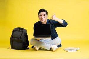 Portrait of Asian male student posing on yellow background photo