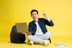 retrato de asiático masculino estudiante posando en amarillo antecedentes foto