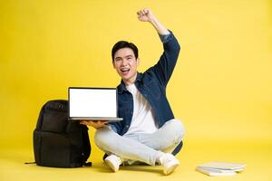 Portrait of Asian male student posing on yellow background photo