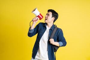 retrato de asiático masculino estudiante posando en amarillo antecedentes foto