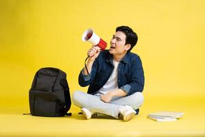 retrato de asiático masculino estudiante posando en amarillo antecedentes foto