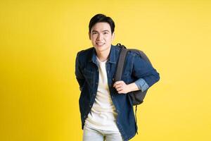 Portrait of Asian male student posing on yellow background photo