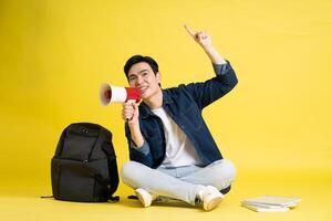 Portrait of Asian male student posing on yellow background photo