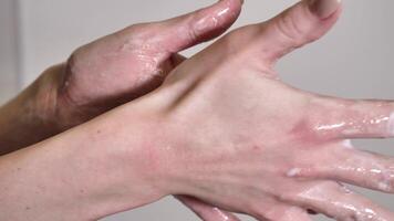 washing woman's hands with soap and water to remove dirt and germs close-up on white background. The fingers move gently and slowly video