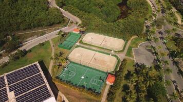 Overhead perspective of sports amenities showcasing basketball and tennis courts, with people actively participating in vibrant tennis game. This scene is set at Secrets Royal Beach Punta Cana hotel. video