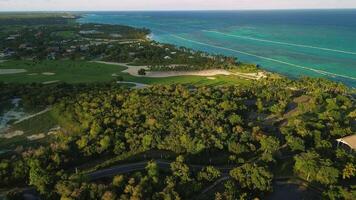 tropisk kust i punta cana. golf kurs, djungel och turkos transparent hav på solnedgång. antenn se video