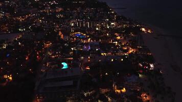 une fascinant drone vue capture une renommé côtier ville pendant une frappant violet coucher de soleil, accentué par le chatoyant lueur de animé ville lumières. vol avant. video