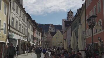 Mars 31, 2024. fussen, Tyskland. altstadt, fuessen, bayern, tyskland. gammal stad i solig väder med människor vilar, kaféer och restauranger. historisk gammal bavarian byggnader på fussen. video