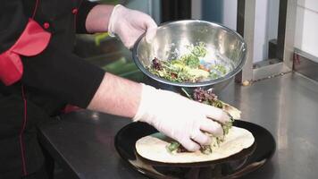 kock matlagning sallad i en professionell kök i en restaurang. händer stänga upp video