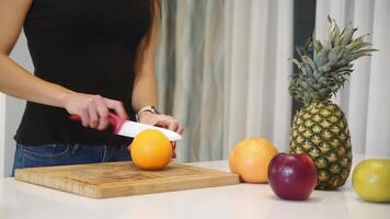 hembra manos corte naranja en un de madera tablero. mujer en el cocina. sano comiendo. crudo alimento. video