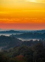 The stunning view from a tourist's standpoint as they go down a hill on a foggy trail with a hill and a background of a golden sky in Forest Park, Thailand. Rainforest. Bird's eye view. Aerial view. photo