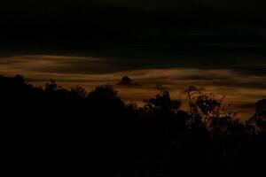 The stunning view from a tourist's standpoint as they go down a hill on a foggy trail with a hill and a background of a golden sky in Forest Park, Thailand. Rainforest. Bird's eye view. Aerial view. photo