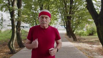 Elderly sport runner man training. Workout cardio outside in park at morning. Active senior people video