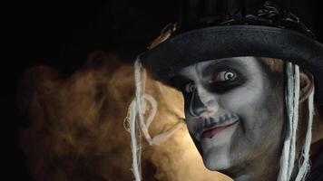 spaventoso uomo nel scheletro Halloween trucco giri testa e sembra in telecamera con occhi largo Aperto video
