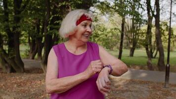 senior sport loper vrouw gebruik makend van slim horloge, bijhouden afstand, controle pulse na geschiktheid training video