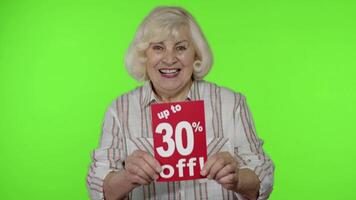 Sénior grand-mère montrant en haut à 30 pour cent de une inscription panneaux, réjouissance remises. noir Vendredi video