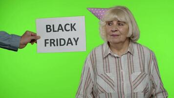 Inscription advertising Black Friday appears next to joyful grandmother with shopping bags video