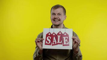 großartig Rabatte. glücklich heiter blond Mann im Blau Hemd zeigen Verkauf Wort Werbung Inschrift video