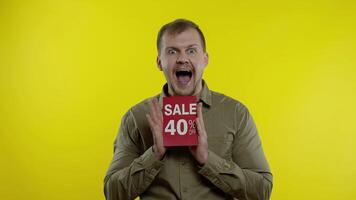 Attractive man showing Sale 40 percent Off inscriptions signs, rejoicing good discounts, low prices video