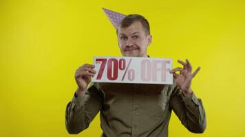 Joyful man showing Sale word and showing Up To 70 percent Off inscription. Black Friday concept video