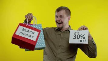 Man showing shopping bags and Up To 30 percent Off inscription, looking satisfied with low prices video