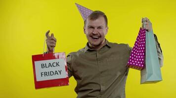 Smiling man showing Black Friday inscription on shopping bags, celebrating, rejoicing good discounts video