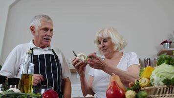 Elderly grandparents eating raw broccoli and cauliflower. Vegetarian diet. Healthy senior family video