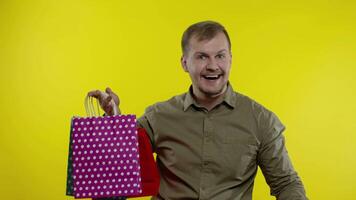 Man showing shopping bags and Up To 50 percent Off inscription, looking satisfied with low prices video