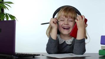 Child schoolgirl laughing and smiling. Learning lessons at home and using digital smartphone video