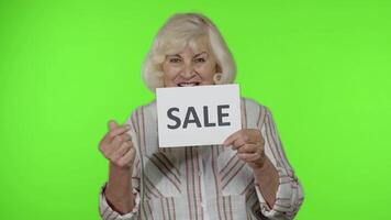 Elderly stylish grandmother smiling and holding Sale word inscription banner. Black Friday video