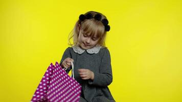 criança menina com compras bolsas mostrando Preto Sexta-feira inscrição, satisfeito com baixo preços descontos video