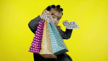 Child girl with shopping bags showing Black Friday inscription, satisfied with low prices discounts video