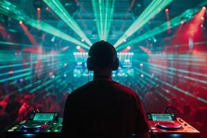 Male DJ on a big rave playing for a big crowd of party people, ravers dancing, big laser show photo