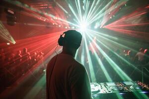 Male DJ on a big rave playing for a big crowd of party people, ravers dancing, big laser show photo