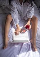 Woman holding wine glass while working on laptop photo