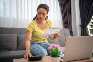 Woman using calculator to check total sum of household bills photo