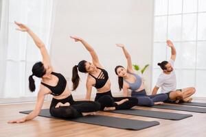 A yoga teacher and her group of students do basic yoga poses in a classroom in a fitness center in the studio. photo